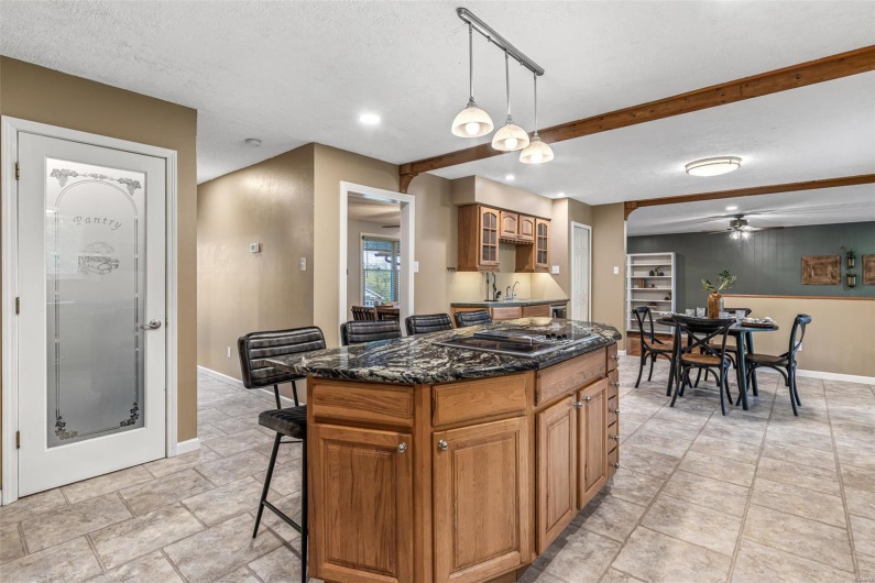 Kitchen with a center island, a kitchen breakfast bar, stovetop with downdraft, baseboards, and ceiling fan
