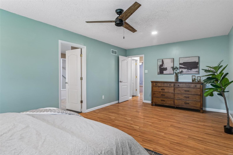 Bedroom with a textured ceiling, baseboards, visible vents, a ceiling fan, and wood finished floors