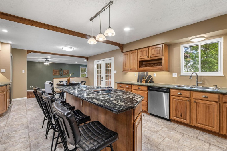 Kitchen featuring a kitchen breakfast bar, stainless steel dishwasher, french doors, a sink, and a center island