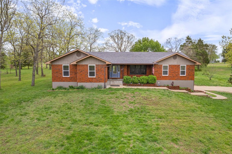 Single story home with brick siding, driveway, a shingled roof, and a front lawn