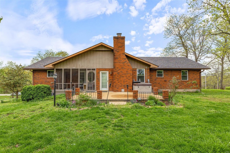 Back of property featuring a chimney, roof with shingles, brick siding, a lawn, and a sunroom