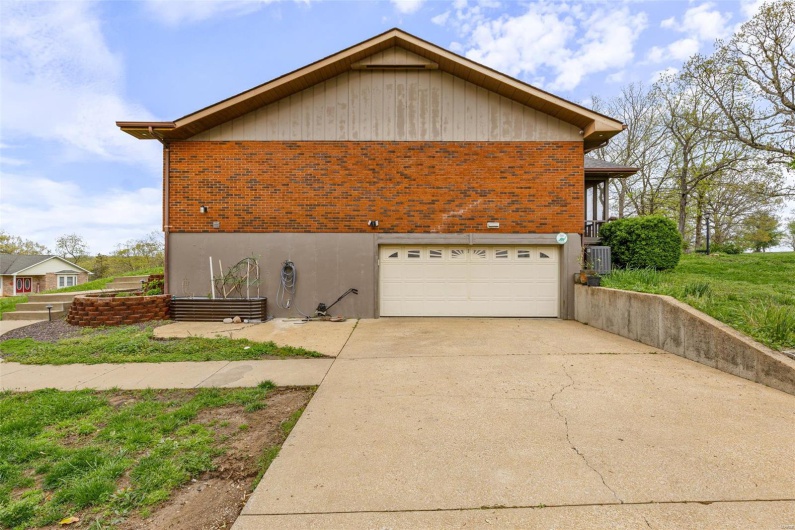 View of home's exterior featuring a garage, brick siding, central AC unit, and concrete driveway