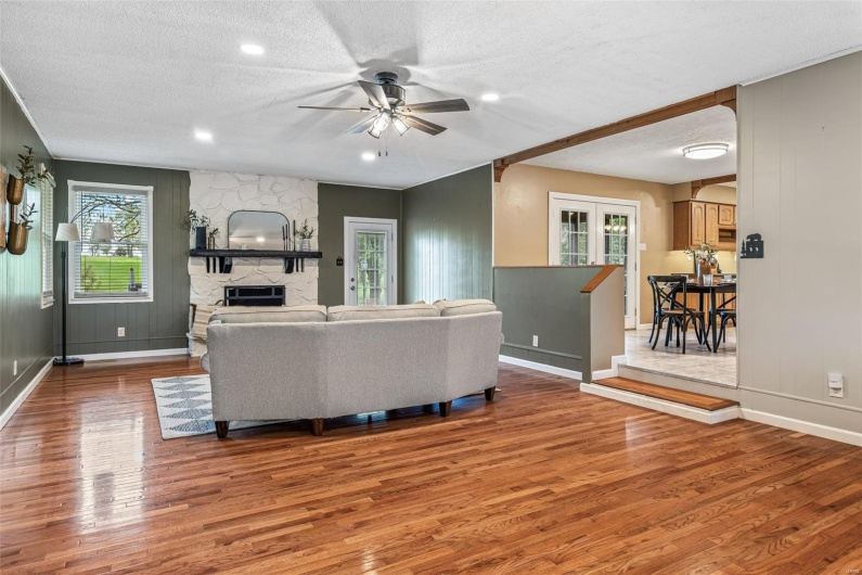 Living area featuring baseboards, a ceiling fan, wood finished floors, and a textured ceiling