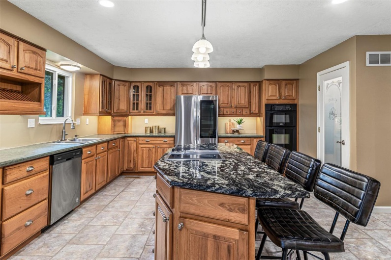 Kitchen with brown cabinets, visible vents, a sink, and black appliances