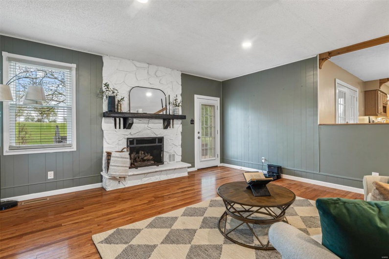 Living area featuring baseboards, a stone fireplace, and wood finished floors