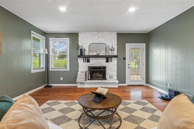 Living room with baseboards, a fireplace, wood finished floors, and a textured ceiling