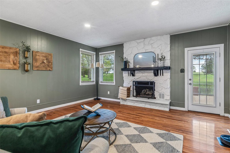 Living room featuring a fireplace, wood finished floors, a textured ceiling, and plenty of natural light
