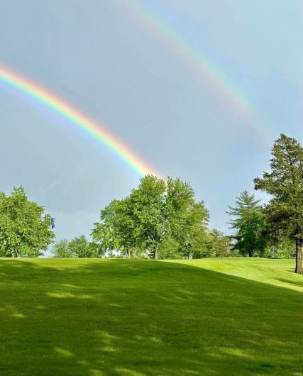 View of community with view of golf course and a lawn