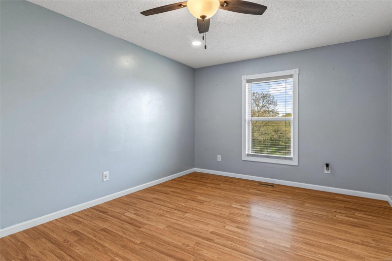 Unfurnished room with baseboards, a ceiling fan, a textured ceiling, and light wood-style flooring