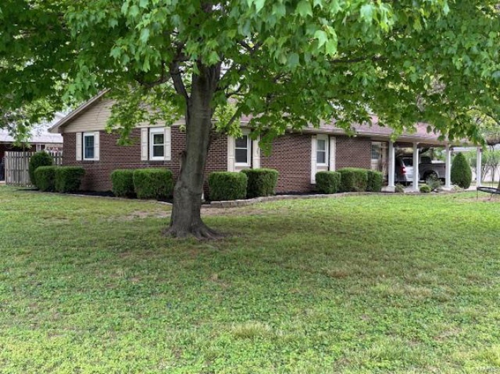 Obstructed view of property featuring brick siding, a carport, and a front yard