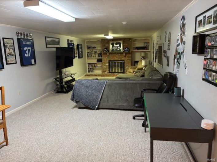 Living area featuring carpet flooring, baseboards, a brick fireplace, and ornamental molding