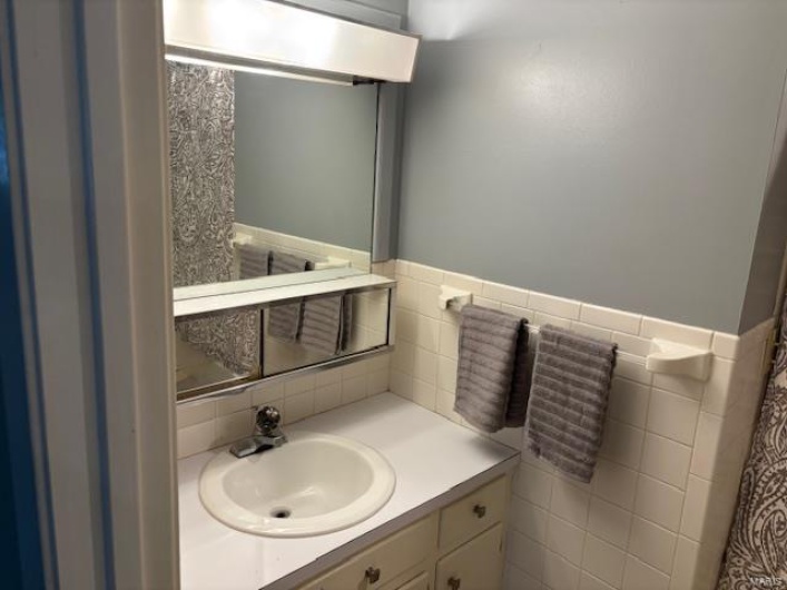 Bathroom with vanity and tile walls