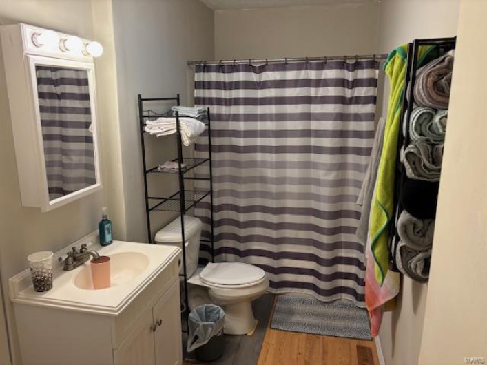 Bathroom featuring a shower with curtain, vanity, toilet, and hardwood / wood-style flooring