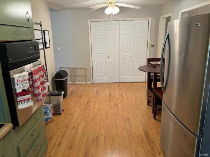 Kitchen featuring ceiling fan, appliances with stainless steel finishes, green cabinets, and light hardwood / wood-style flooring