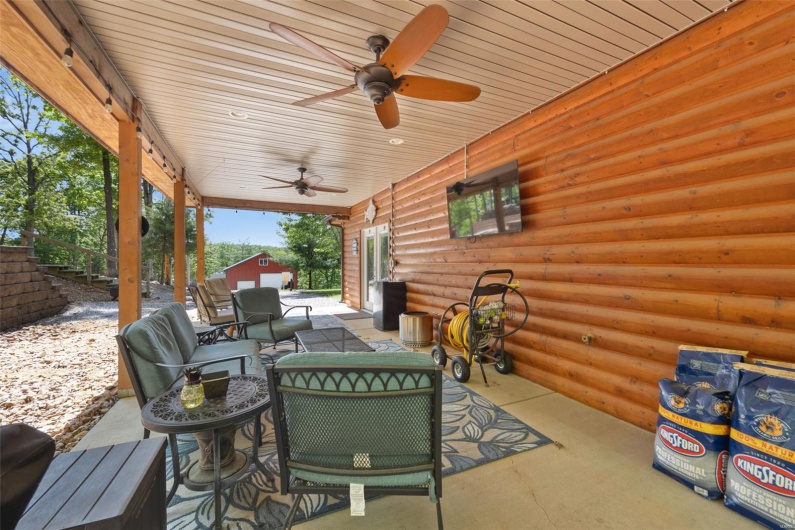 View of patio featuring a ceiling fan, an outdoor living space, a storage shed, and an outbuilding