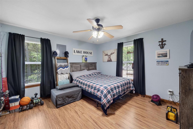 Bedroom with multiple windows, light wood finished floors, a ceiling fan, and baseboards