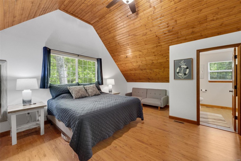 Bedroom with wood ceiling, lofted ceiling, wood finished floors, connected bathroom, and baseboards