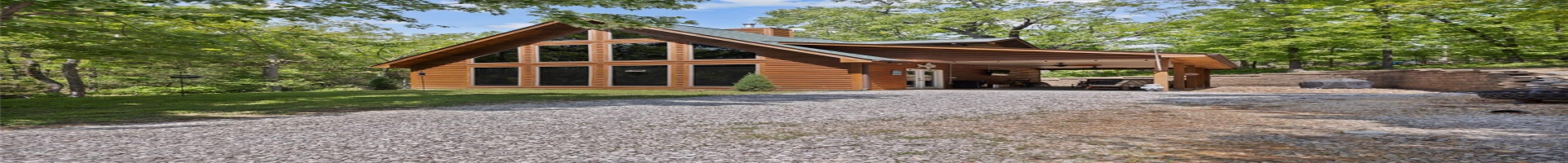 Residential For Sale View of front facade featuring driveway, a chimney, faux log siding, a carport, and a ceiling fan