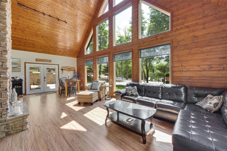 Living room with high vaulted ceiling, wooden ceiling, wood finished floors, french doors, and rail lighting