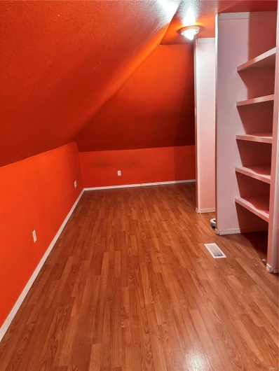 Additional living space with lofted ceiling, wood-type flooring, and a textured ceiling