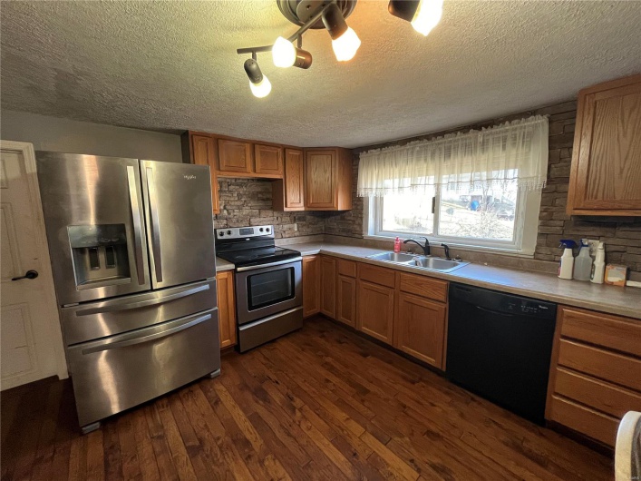 Kitchen featuring dark hardwood / wood-style flooring, sink, stainless steel appliances, and a textured ceiling