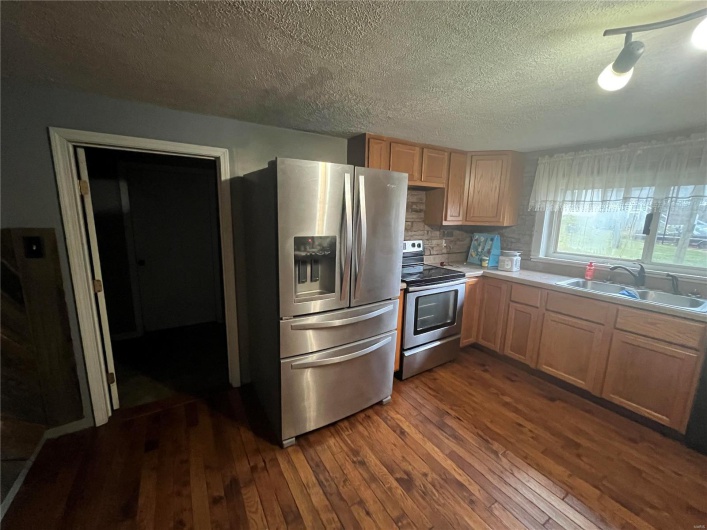 Kitchen featuring sink, a textured ceiling, appliances with stainless steel finishes, dark hardwood / wood-style flooring, and decorative backsplash