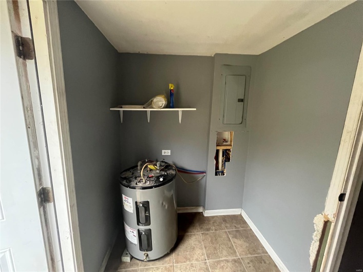 Utility room featuring electric panel and electric water heater
