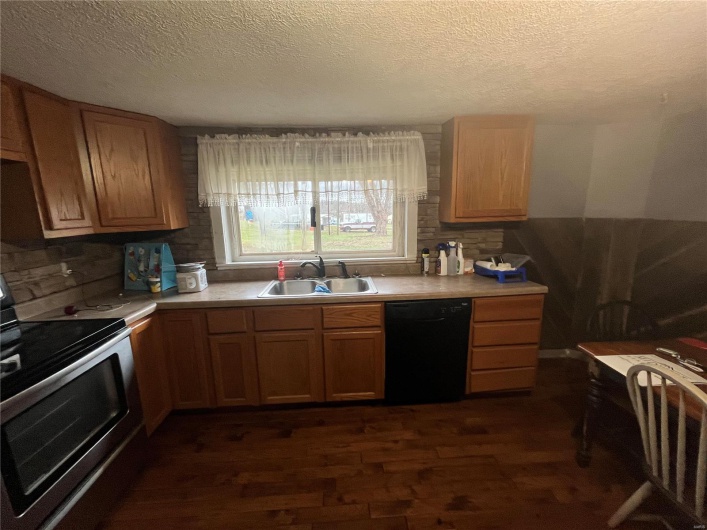 Kitchen with sink, dark wood-type flooring, black dishwasher, a textured ceiling, and stainless steel electric range oven