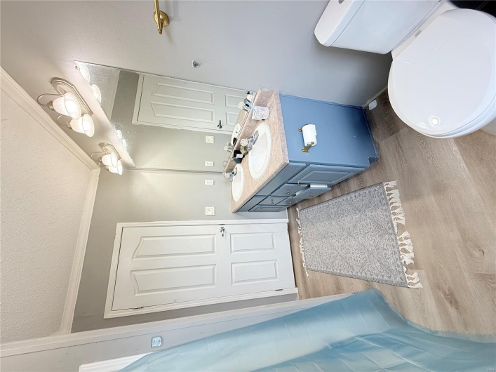 Full bath with toilet, double vanity, a sink, and wood finished floors