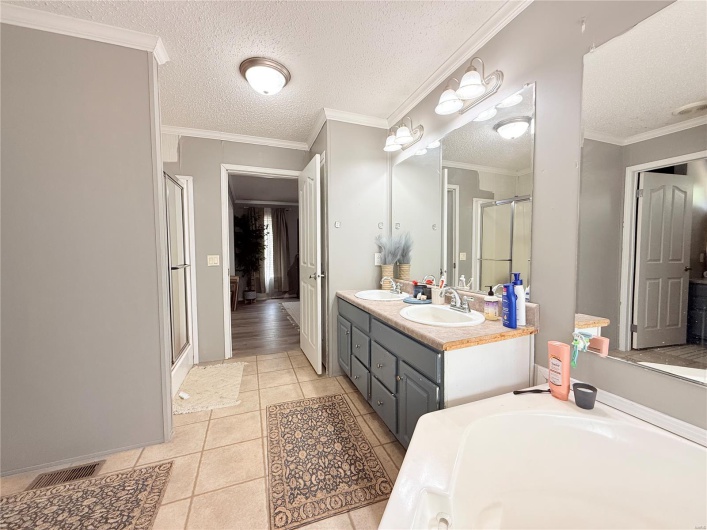 Full bath with a stall shower, a textured ceiling, a sink, and tile patterned floors