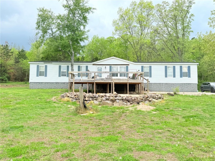 Rear view of house with a deck and a yard