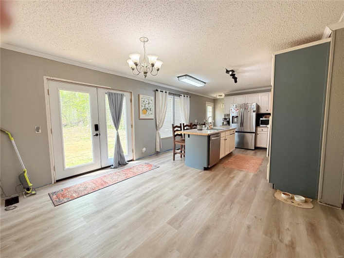 Kitchen with a textured ceiling, stainless steel appliances, light wood-style flooring, and a sink