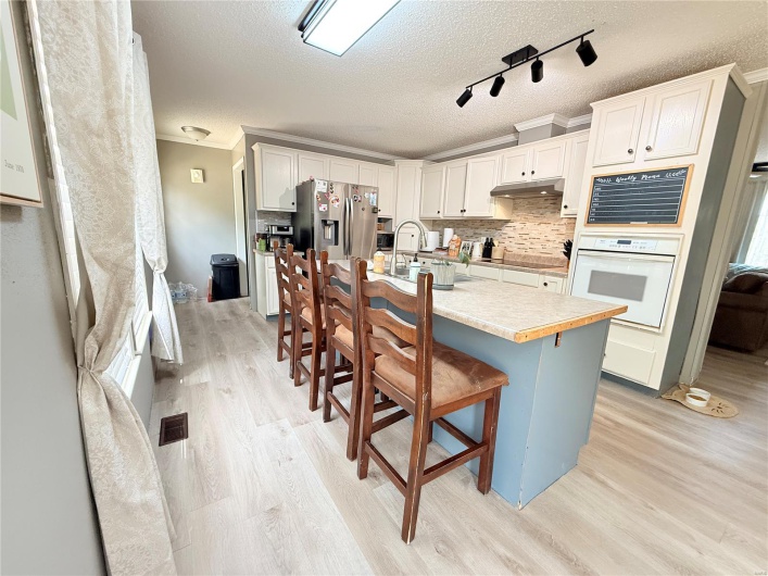 Kitchen with light wood-type flooring, white oven, stainless steel fridge, and a sink