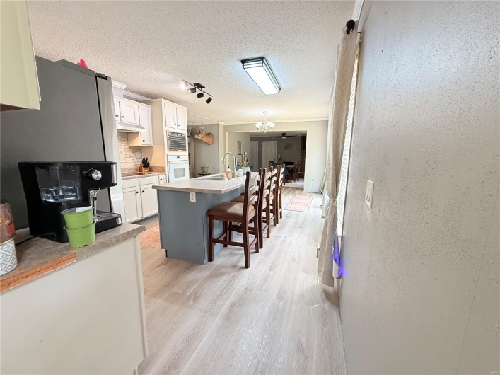 Kitchen with light wood-style flooring, white cabinets, a breakfast bar, freestanding refrigerator, and backsplash