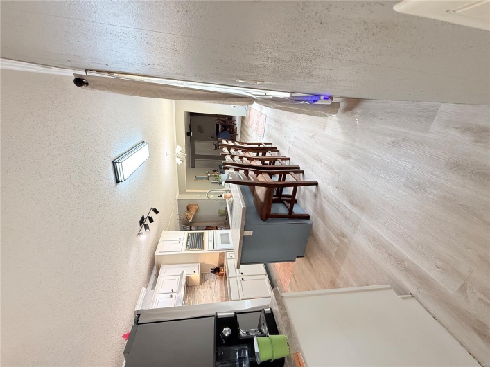 Kitchen with a breakfast bar area, oven, light wood-style flooring, and white cabinets