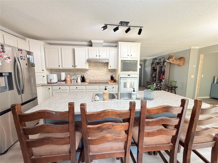 Kitchen with white cabinetry, white oven, and stainless steel refrigerator with ice dispenser