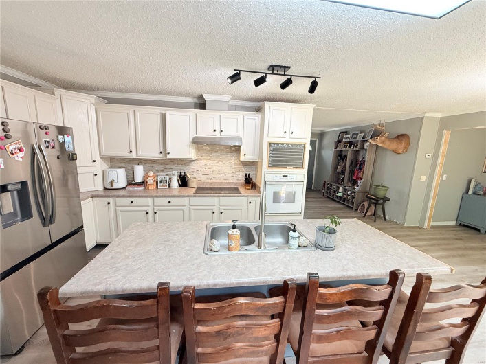 Kitchen featuring white cabinets, stainless steel refrigerator with ice dispenser, and white oven