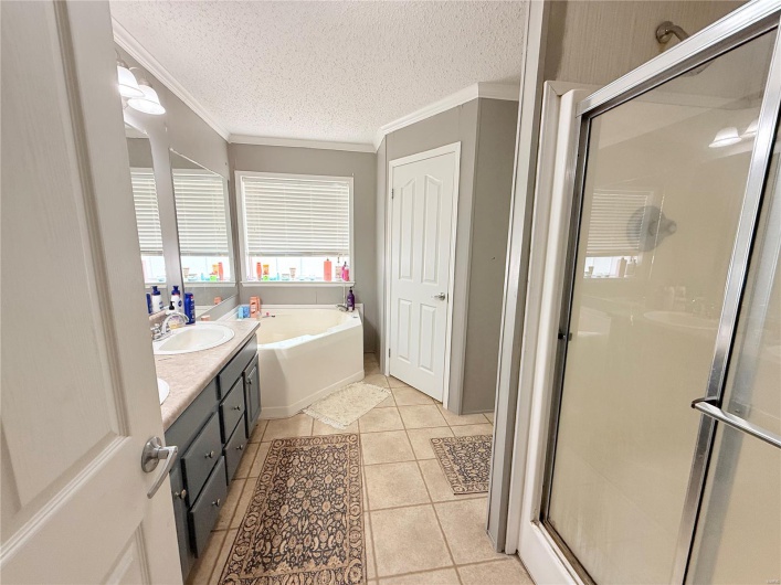 Bathroom featuring crown molding, a sink, a stall shower, a bath, and tile patterned flooring