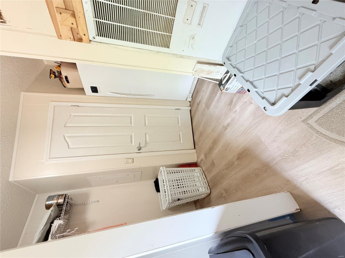 Bedroom featuring refrigerator, a textured ceiling, and light wood-style flooring