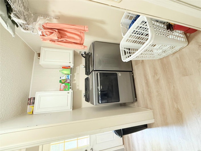 Washroom with light wood-style flooring, washing machine and clothes dryer, cabinet space, and a textured ceiling