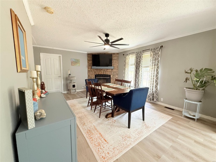 Dining space with a fireplace, a textured ceiling, ceiling fan, and light wood-style floors