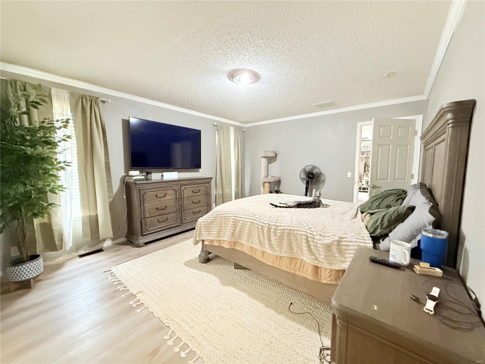 Bedroom featuring a textured ceiling, light wood-type flooring, and ornamental molding