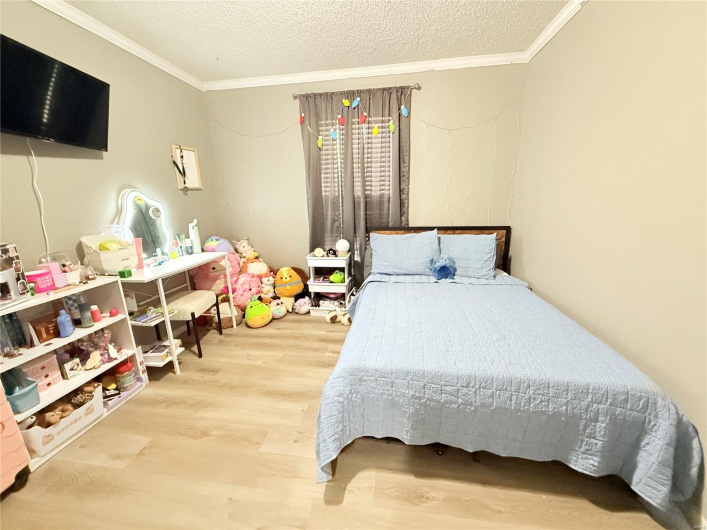 Bedroom featuring wood finished floors, a textured ceiling, and ornamental molding
