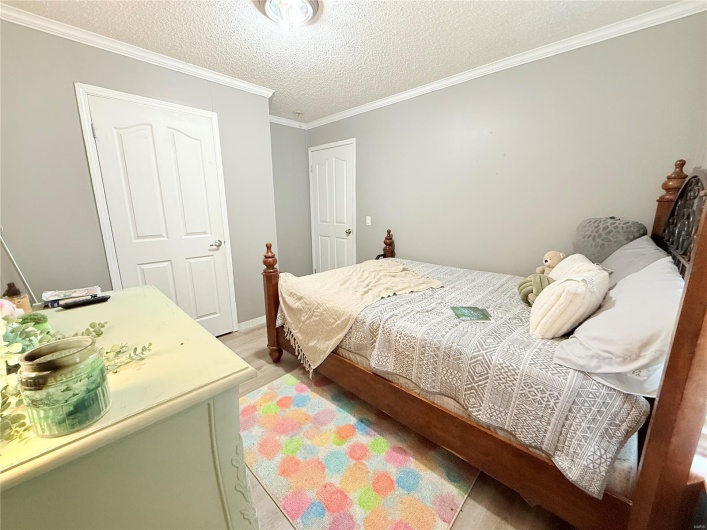 Bedroom featuring crown molding, a textured ceiling, and light wood-type flooring