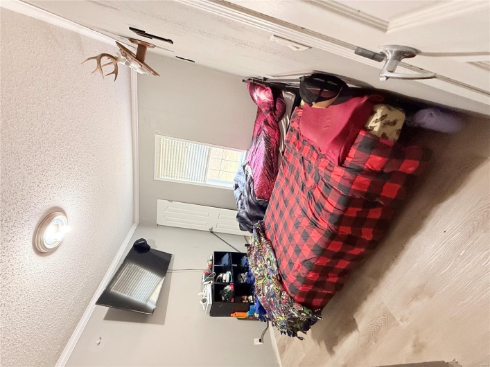 Bedroom featuring crown molding, a textured ceiling, and wood finished floors