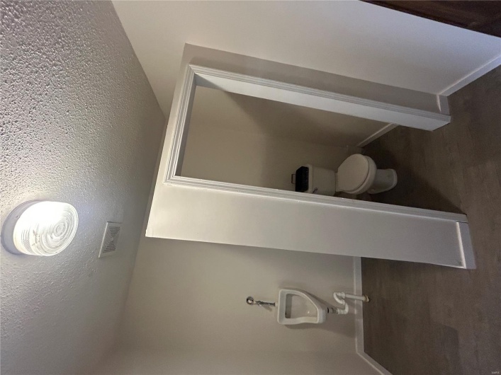 Bathroom featuring a textured ceiling, visible vents, toilet, and baseboards
