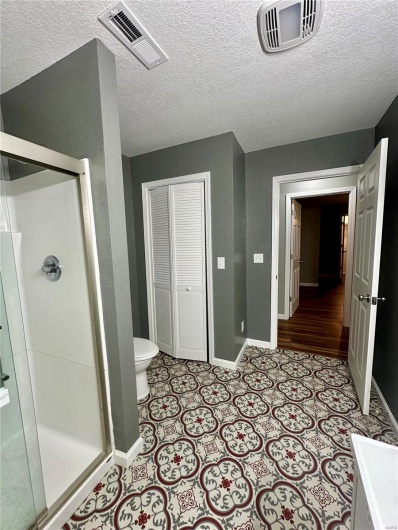 Bathroom with baseboards, visible vents, a shower stall, and toilet