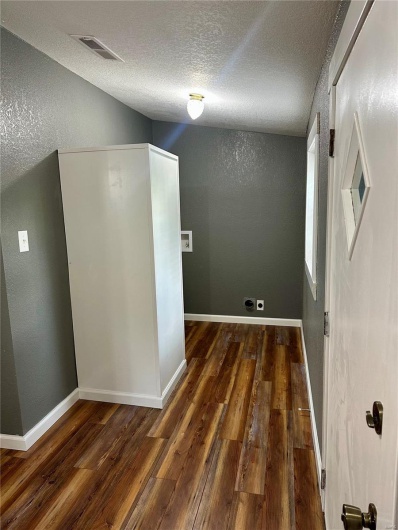 Hall with visible vents, wood finished floors, a textured ceiling, and a textured wall