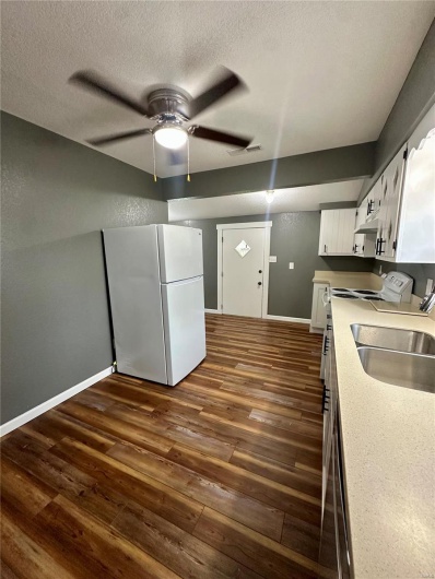 Kitchen featuring white cabinets, freestanding refrigerator, baseboards, dark wood finished floors, and a ceiling fan
