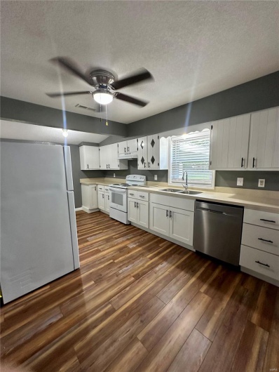 Kitchen with dark wood-style floors, a sink, stainless steel dishwasher, white range with electric cooktop, and freestanding refrigerator